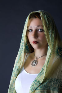 Portrait of young woman in with dupatta on head against black background