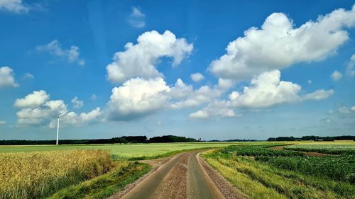 Panoramic view of road amidst field against sky