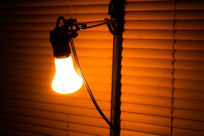 Low angle view of illuminated light bulb hanging on ceiling