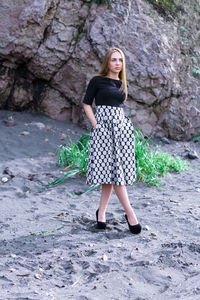 Young woman standing against rock formations at beach