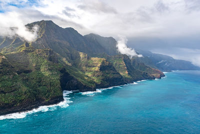 Scenic view of sea and mountains against cloudy sky