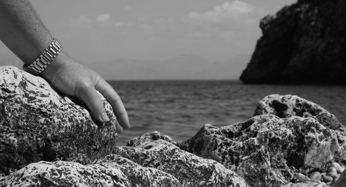 Cropped hand of man on rock at beach