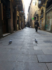 Man walking on footpath amidst buildings in city