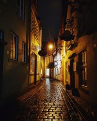 Empty alley amidst buildings at night