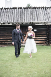 Smiling bride and groom holding hands in yard