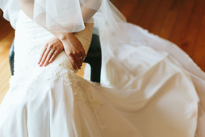 Midsection of bride sitting on stool in wedding ceremony