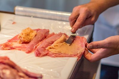 Cropped hands of man preparing meat on table