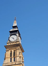 Low angle view of clock tower against blue sky