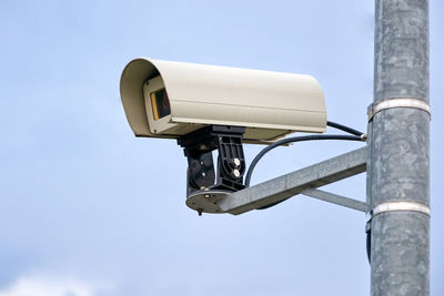 Low angle view of security camera against sky