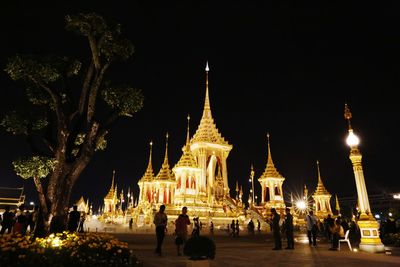 People at temple against sky at night