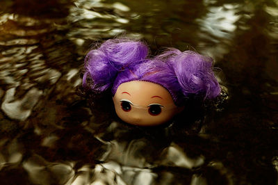 Close-up of abandoned doll in puddle