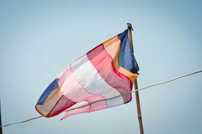 Low angle view of flag against clear blue sky