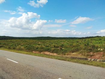 Scenic view of road amidst field against sky