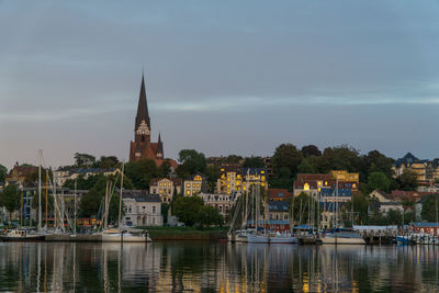 Sailboats in building by city against sky