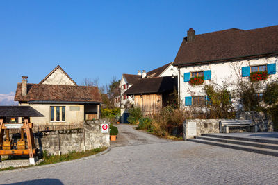 Street amidst houses and buildings against blue sky