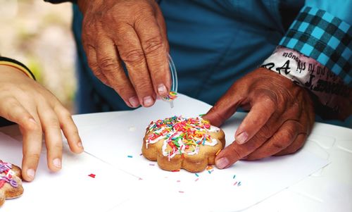 Only hands. aged woman decorates cookies.