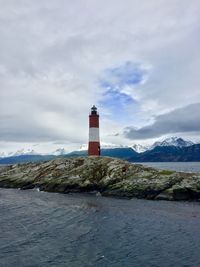 Lighthouse by sea against sky