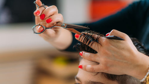 Close-up of a hairdresser's hands with scissors, cutting boy's hair.