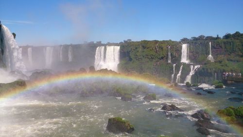 Scenic view of waterfall against rainbow in sky