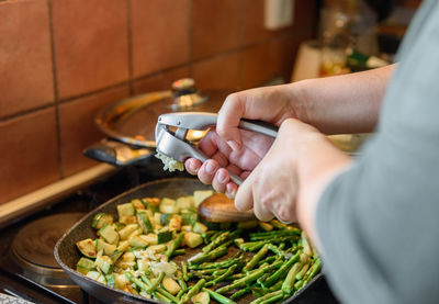 Close-up photo of woman cooking lunch, squeezing garlic with garlic press over frying pan