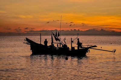 Silhouette fishing boats in sea against sky during sunset