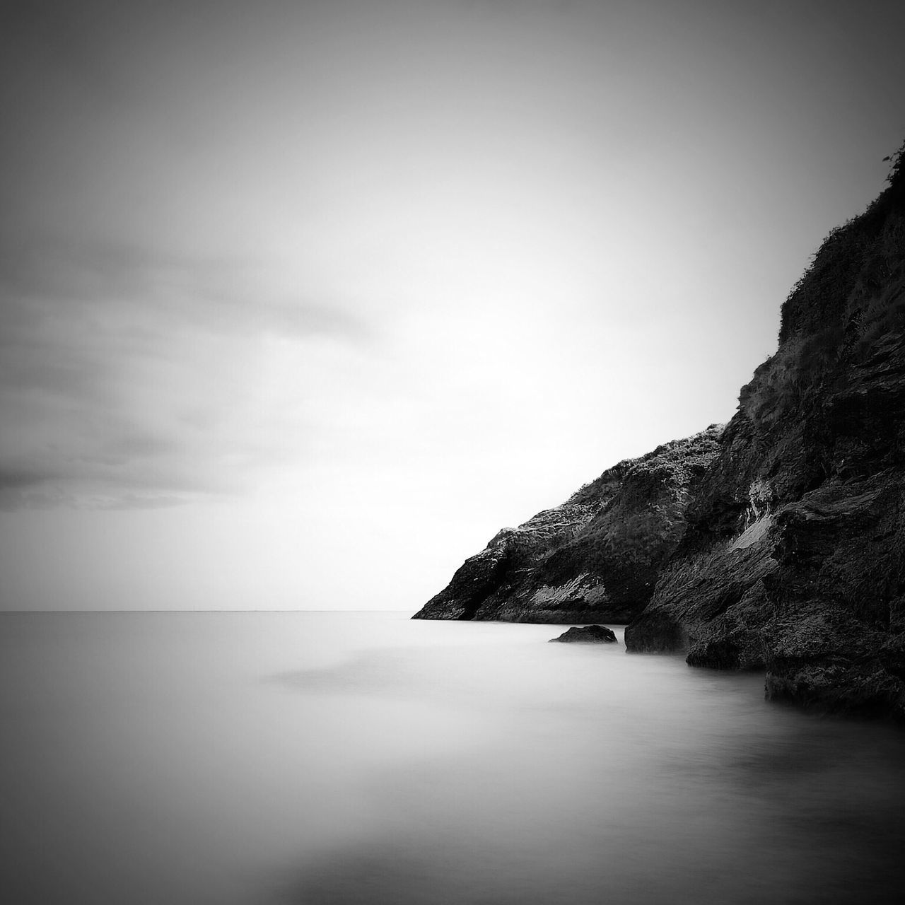 water, sea, tranquil scene, waterfront, tranquility, scenics, beauty in nature, horizon over water, copy space, sky, mountain, nature, clear sky, idyllic, calm, rock - object, cliff, rock formation, built structure, outdoors