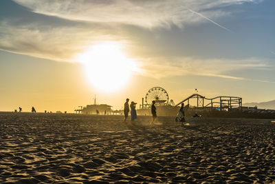 Silhouette people on beach against sky during sunset