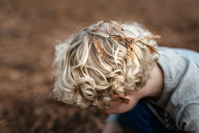 Pine needle leaves on head of curly haired child