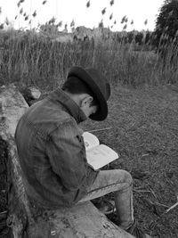 Side view of young man sitting on field