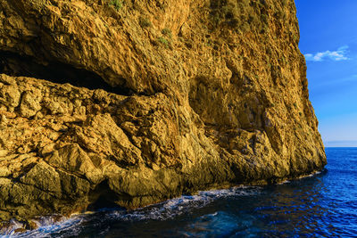 Rock formation at sea shore against sky