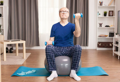 Full length of senior man exercising at home