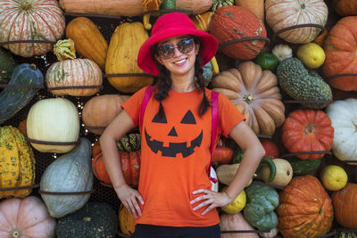 Portrait of a smiling young woman standing by pumpkins