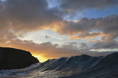 Scenic view of  wave against sky during sunset