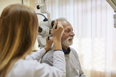 Ent physician examining ear of a senior man