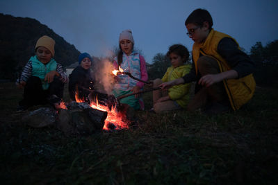 Friends sitting on campfire at night