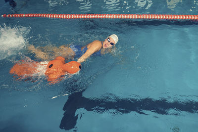 Woman with cpr dummy standing at swimming pool