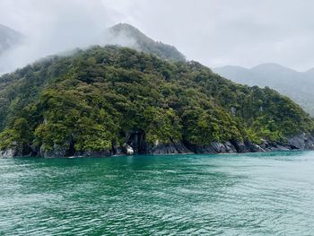 Scenic view of sea by mountains against sky