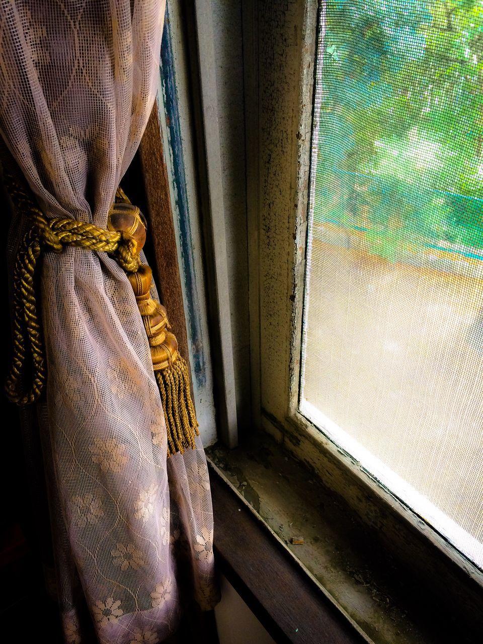 indoors, window, curtain, one person, glass - material, door, transparent, sunlight, built structure, day, architecture, closed, house, home interior, close-up, wall - building feature, pattern, looking through window, low section, wall