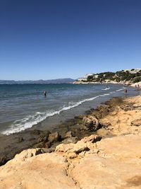 Scenic view of beach against clear blue sky