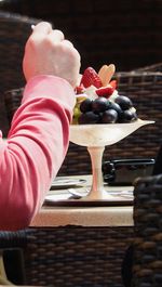 Midsection of person holding ice cream on table