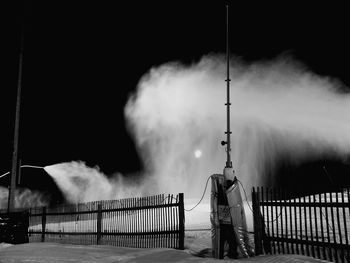 Man standing by railing against sky at night