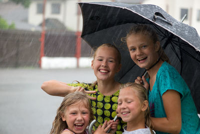 Portrait of friends enjoying in rain
