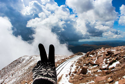 Peace gesture against snow covered rocky landscape