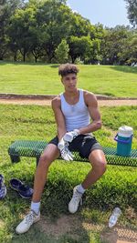 Full length portrait of young man sitting on field