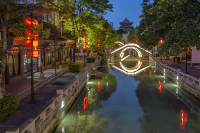 Illuminated bridge over canal in city at night