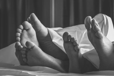 Low section of family relaxing on bed at home