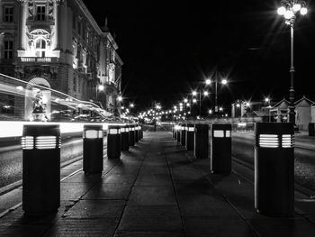 Illuminated street amidst buildings in city at night