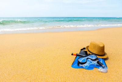 Hooded chairs on sand at beach against sky