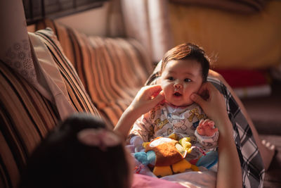 Mother playing with daughter cheek at home