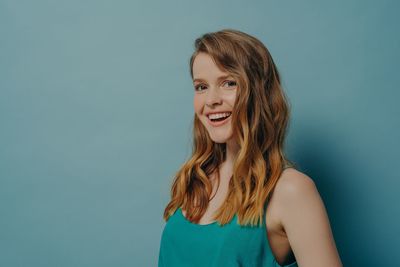 Portrait of smiling young woman against blue background